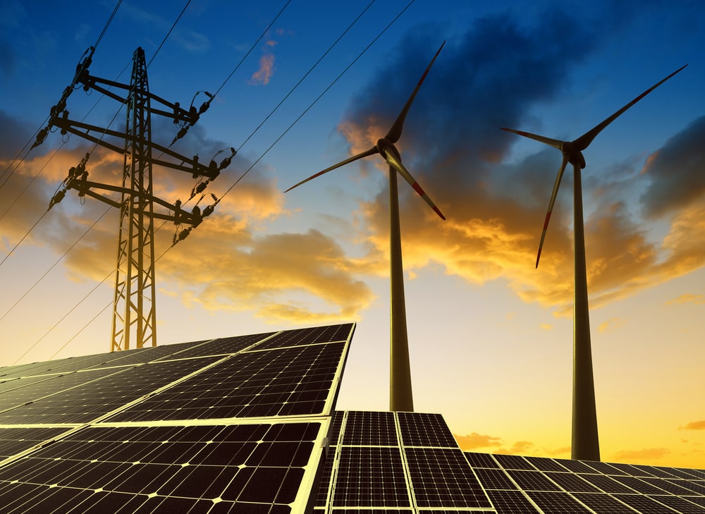 Solar panels, transmission tower and windmills during dawn